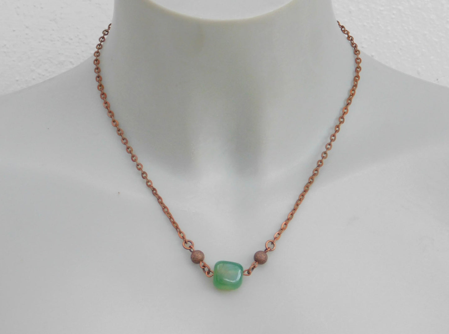 Eine kurze kupferfarbene Halskette mit einem grünen Achat